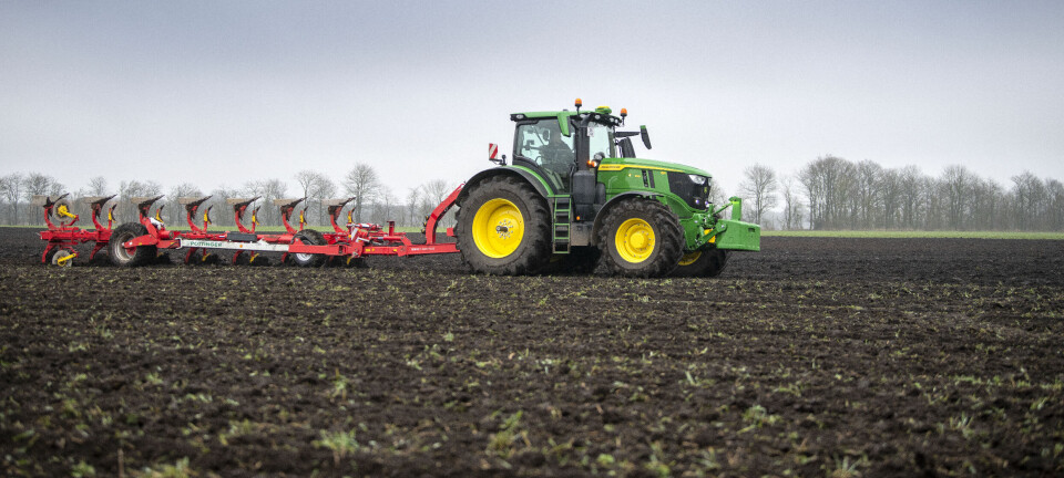 John Deere traktor med plog på jordet