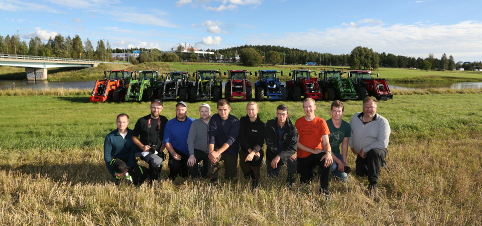 10 menn står på kne med 9 traktorer bak.