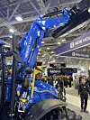 New Holland traktor med en hevet New Holland frontlaster utstilt på stand.