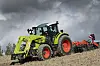 Claas Arion 440 på jordet med harv bak. Himmelen over er preget av mørke skyer