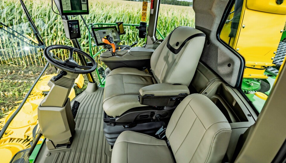 Førerplass med Active Seat2. Bilde av førerplassen i snitteren fra John Deere der vi skimter maisåkeren utenfor.