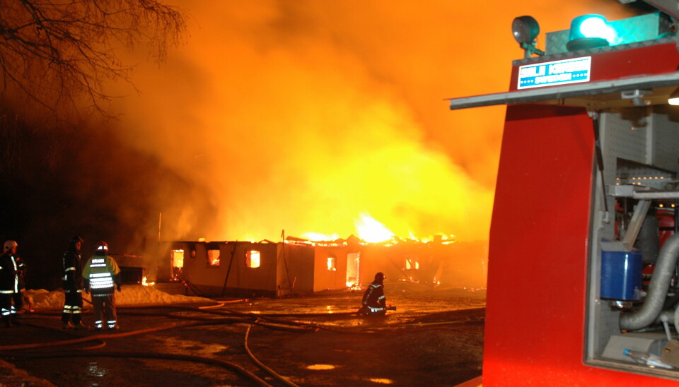 Brann i en låve, overtent driftsbygning, med brannmannskap i ferd med å prøve å få kontroll over brannen.