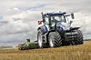 En New Holland T7 traktor ute på jordet med redskap bak.