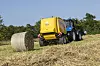 Rundballepressa New Holland Roll-Belt i drift med halm ute på en åker.
