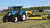 New Holland traktor med pickuprive fra ROC bak i drift på jordet