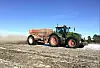 Fendt traktor med kalkvogn bak ute på et brunt jorde