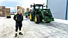 Hans-Terje Rolsdorph poserer med en John Deere traktor i bakgrunnen og en rekke potetkasser stablet bak ham.