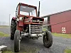 Massey Ferguson 148 parkert på tunet med en rød driftsbygning i bakgrunnen