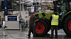 To men står ved en Claas-traktor inne i en fabrikkhall