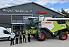 Fem personer og en Claas tresker plassert utenfor lokalene til Bergan Maskinsalg