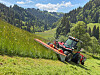 traktor i bratta med slåmaskin.