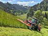 traktor i bratta med slåmaskin.