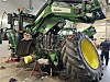 Traktor på verksted med hjulene fjernet og panseret oppe