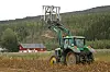 John Deere traktor i potetåker med slangeopptaker i frontlasteren