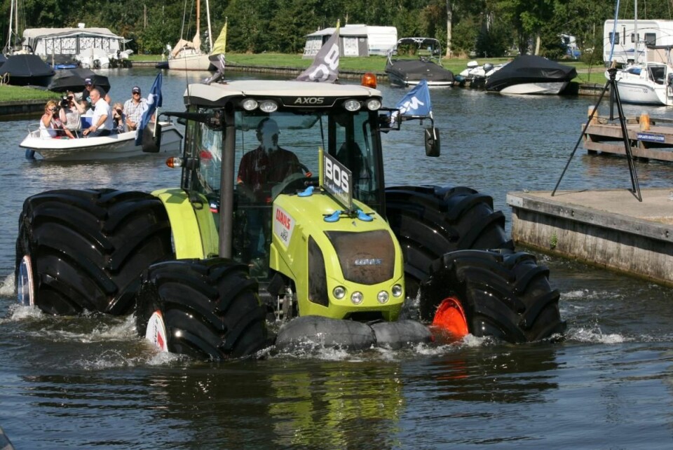 Claas Axos 320 traktor med svære dekk fra Mitas har blitt kjørt ut i en innsjø ved en campingplass og traktoren flyter i vannet.