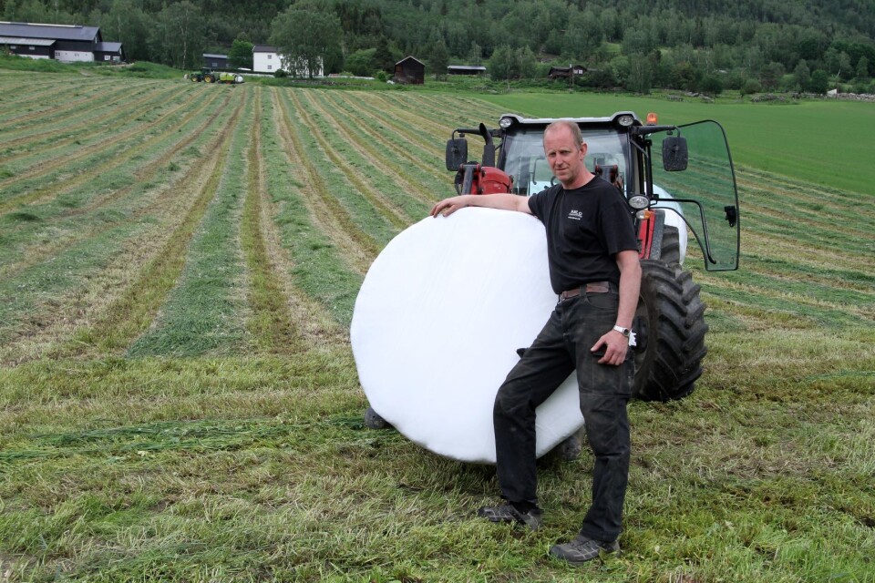 Pål Klomstad poserer med en rundballe og enga i bakgrunnen.