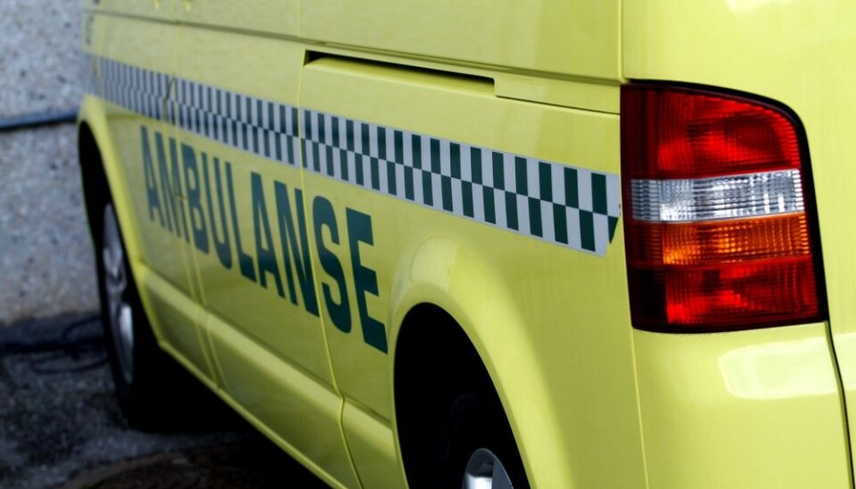 En person omkom etter å ha kommet i klem under en traktor. Ambulanse parkert foran en bygning.