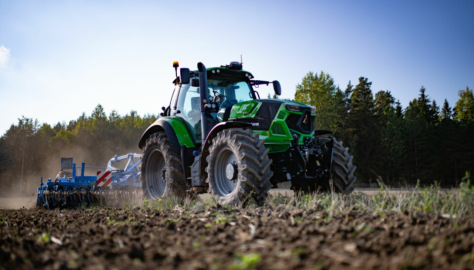 Deutz-Fahr traktor drar harv i en åker.