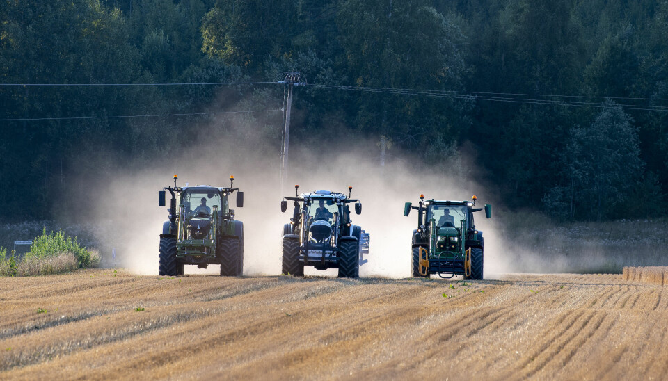 Tre traktorer kjører ved siden av hverandre i stubben på et jorde med støvskyen virvlende bak dem. Valtra N155, Fendt 516 og John Deere 6R150.