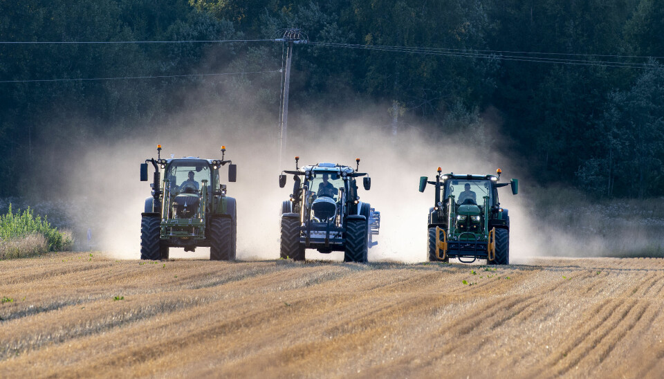 Tre traktorer kjører ved siden av hverandre i stubben på et jorde med støvskyen virvlende bak dem. Valtra N155, Fendt 516 og John Deere 6R150.