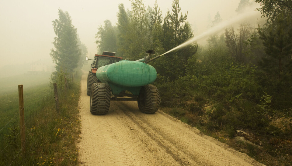 Froland 20080612:Røyken ligger tett over tettstedet Belland der det ble utført evakuering torsdag ettermiddag. Her prøver en lokal bonde å fukte skogen med vann fra en tank på traktoren.Foto: Tor Erik Schrøder / SCANPIX