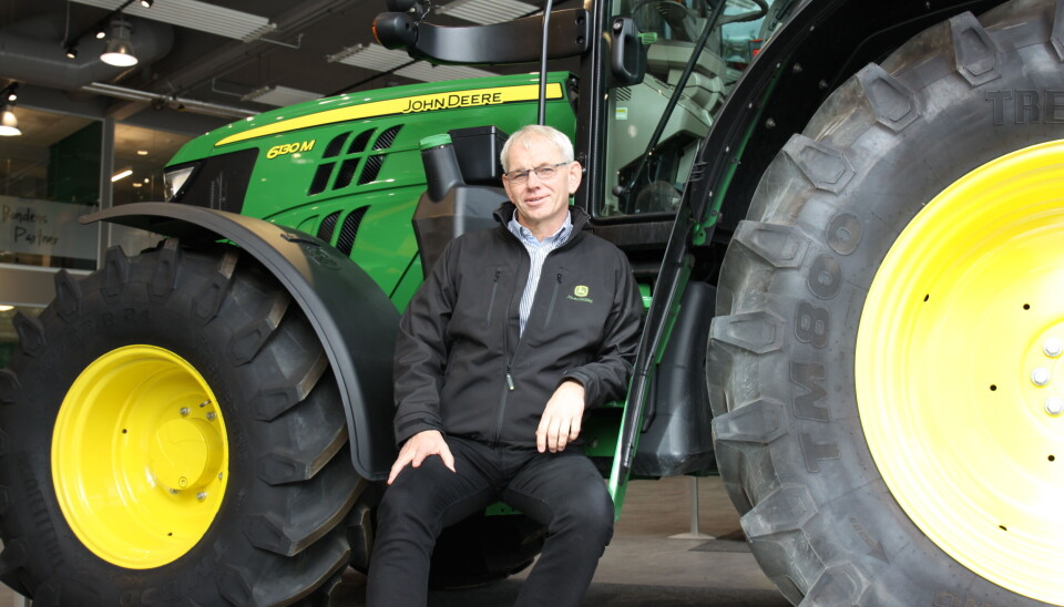 Frode Dahl sittende på stigtrinnet på en John Deere M-serie