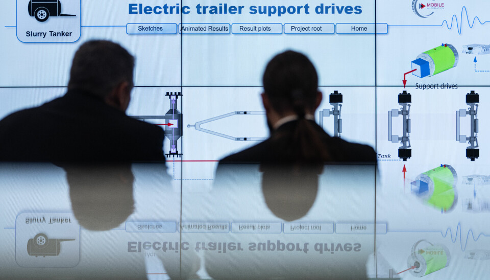 To menn pp Agritechnica 2023 foran en skjerm med teksten 'Electric trailer support drives'